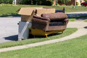 Old couch and cardboard boxes left on the curb in a suburban neighborhood