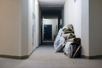 Hallway with stacked bags and rolled mats against the wall in an empty corridor