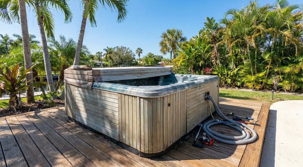 Old hot tub on a wooden deck in a tropical Tampa Bay yard, ready for removal