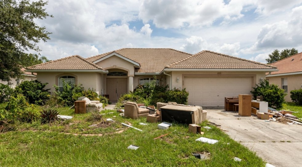Cluttered Tampa Bay home with furniture and debris left in the yard after eviction